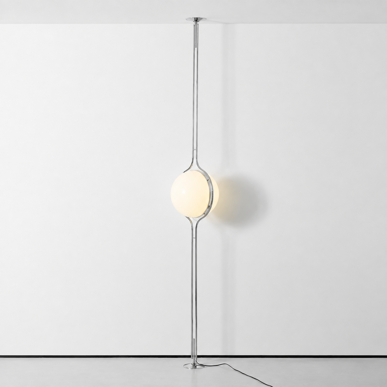 Oris floor to ceiling lamp in Gold in a bright living room beside a black sideboard, full length