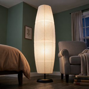 Anara floor lamp glowing in a green bedroom beside an armchair, matte black dome base