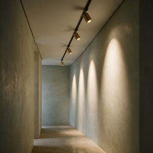 Vantre track light in gold, four heads raking a limewash plaster corridor wall, black track