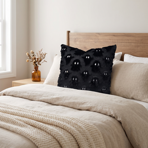 Midnight Ghost plush cushion on a bed in a light modern bedroom