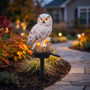 Solar owl stake light glowing along a garden path at dusk