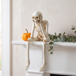 Skeleton figurine on a white mantelpiece with a small gourd