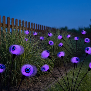 Purple glowing eye orbs among ornamental grasses at dusk
