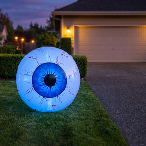 Blue iris inflatable eyeball on a lawn beside a driveway at dusk