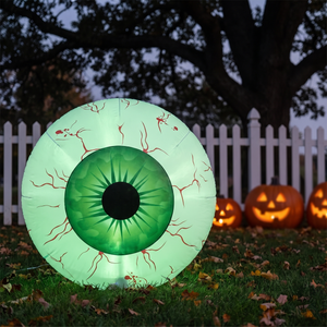 Green iris inflatable eyeball on a lawn by a picket fence at twilight