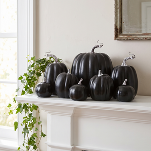 Black decorative pumpkins on a white mantelpiece