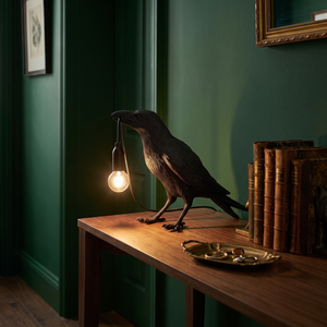 Marble black raven lamp lit on a console table in a green hallway