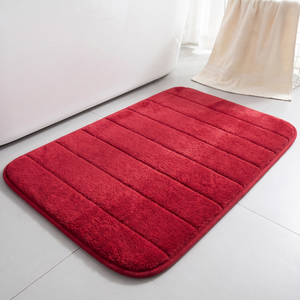 Red bath mat beside a white tub