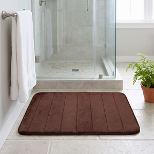 Brown bath mat on a stone tile bathroom floor