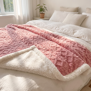 Blush pink sherpa fleece blanket across a bed