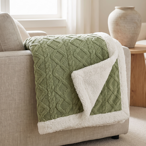 Matcha green sherpa fleece blanket folded over a sofa