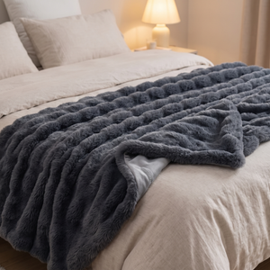 Shadow grey faux fur throw across a bed