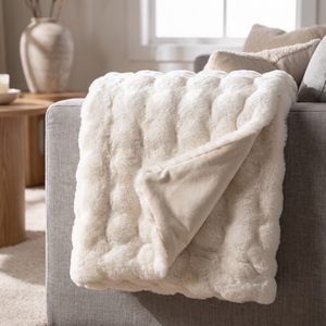 Ivory cream faux fur throw folded over a sofa arm