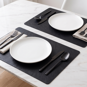 Black faux leather placemats on a marble dining table