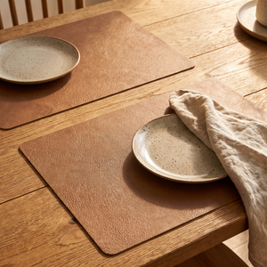 Light coffee faux leather placemats on a rustic oak table