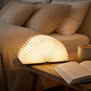 Wood finish book lamp glowing on a bedside table