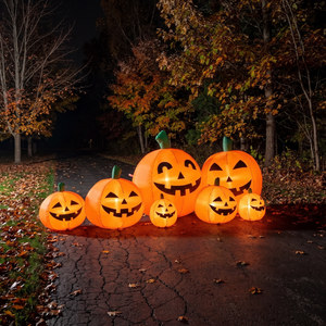 7ft lighted inflatable pumpkin row glowing along a driveway at night
